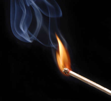 Lit match with smoke on black の写真素材