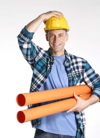 Construction worker holding a yellow helmet and carrying building materialsの写真素材