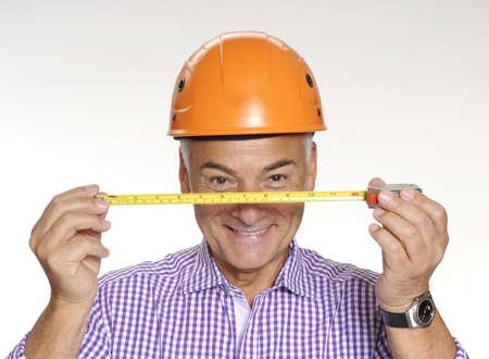 Senior man with safety hat holding measuring tape