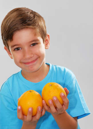 Little kid holding oranges against white backgroundの写真素材