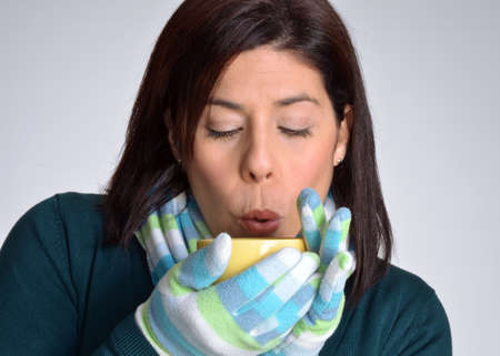 Woman drinking a hot drink from a yellow cupの写真素材