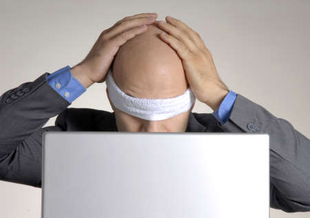 Blindfolded bald man using a computerの写真素材