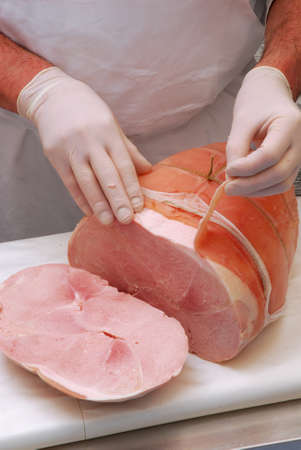 Butcher is peeling the prosciutto skin in a butcher shop の写真素材
