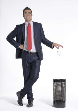 Young businessman dropping paper into the trash binの写真素材