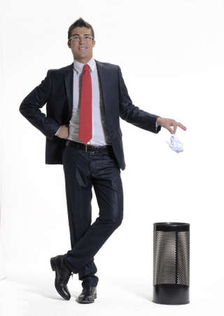 Young businessman dropping paper into the trash binの写真素材
