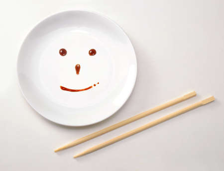 Smiley face on plate with chopsticksの写真素材