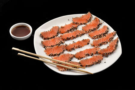 A plate of salmon sashimi with sesame seedsの写真素材
