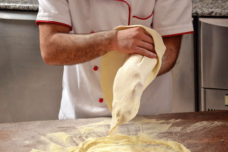 Cook preparing pizza dough.