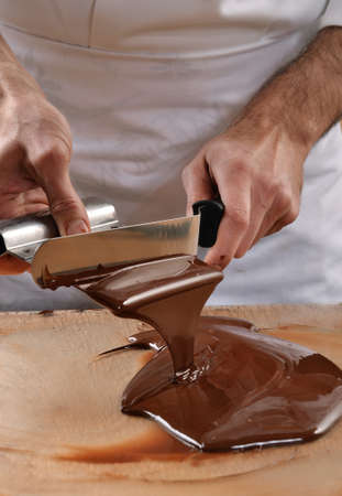 Cook mixing chocolate cream with professional chocolate spatula. Melted dark chocolate.の写真素材