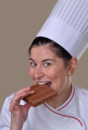 Happy cook woman biting tasting chocolate bar.Eating chocolate.の写真素材