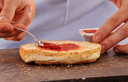 Cook adding ketchup sauce on burger bread.の写真素材
