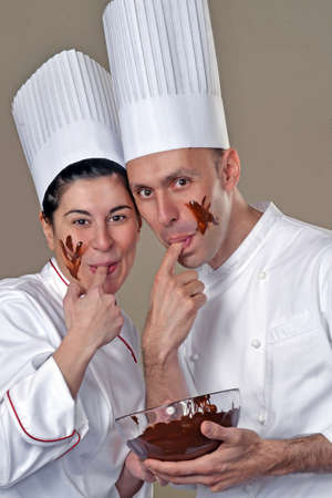 Funny young cook couple tasting chocolate cream.の写真素材