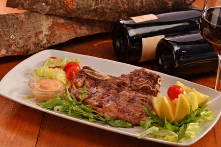 Grilled beef steak dish on red wine bottles and rustic backgroundの写真素材