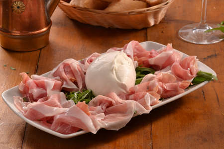 Sliced prosciutto ham and mozzarella cheese dish.の写真素材