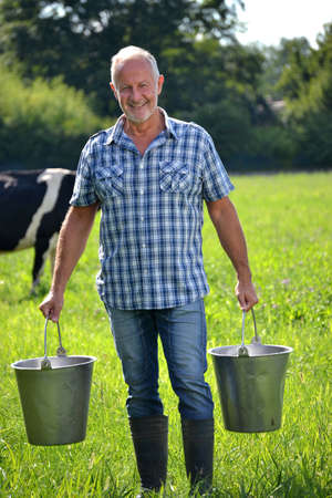 Farmer holding buckets after milking cowの写真素材