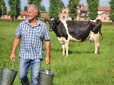 Farmer holding buckets after milking cowの写真素材