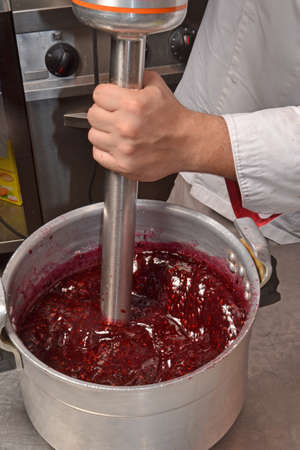 Cook preparing brewing and blending blackberry cream for jam.の写真素材