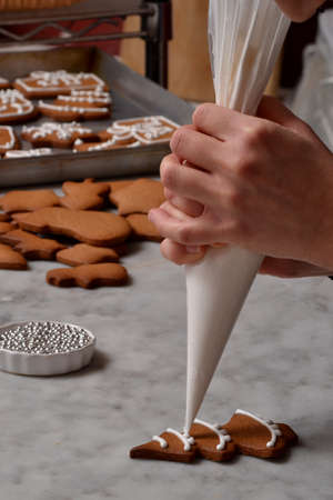 Pastry chef woman preparing christmas cookies holding a vanilla cream cone.の写真素材
