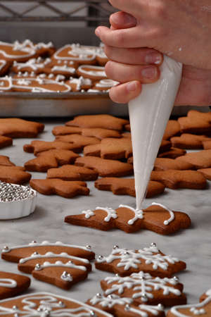 Pastry chef hands preparing christmas cookies holding a vanilla cream cone.の写真素材