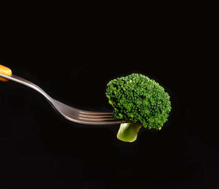 Hot broccoli on fork.On black background.の写真素材