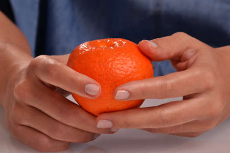 Female hand holding tangerine fruit.