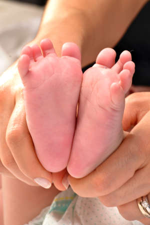 Mother hold feet of newborn