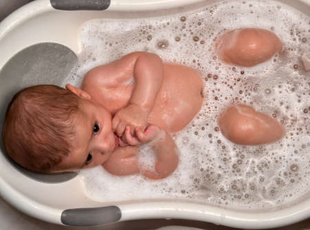 Baby boy bathing in the bathtub by Mother.Mother washing baby in bathtubの写真素材