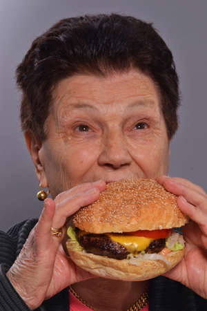 Grandmother eating burgerの写真素材