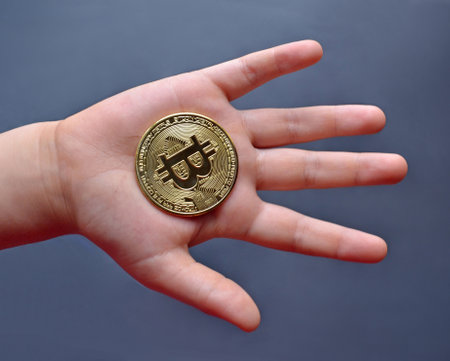 Kid hand hold a bitcoin cryptocurrency tokenの写真素材