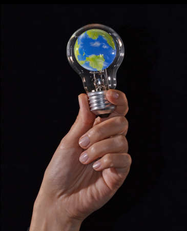 Hand hold a planet earth globe inside a bulb light lamp on global idea concept.の写真素材