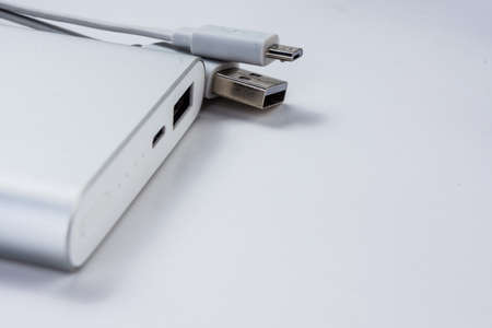 Modern technology power bank. Wired external portable battery for charge cell phone, smartphone and other devices isolated on abstract blurred white background. Urban and travelling lifestyle conceptの写真素材
