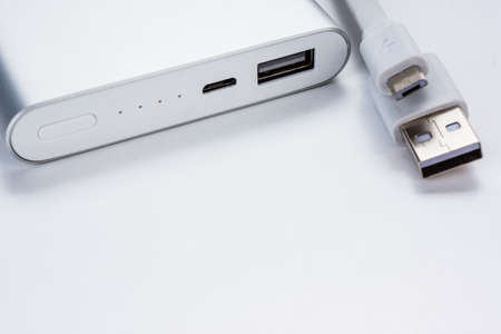 Modern technology power bank. Wired external portable battery for charge cell phone, smartphone and other devices isolated on abstract blurred white background. Urban and travelling lifestyle conceptの写真素材