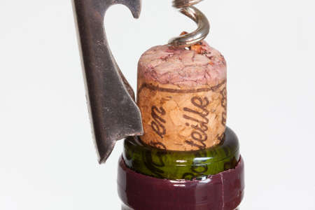 Corkscrew pulling a cap on a bottle neck