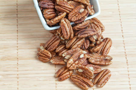 Pecans in a cup on bamboo