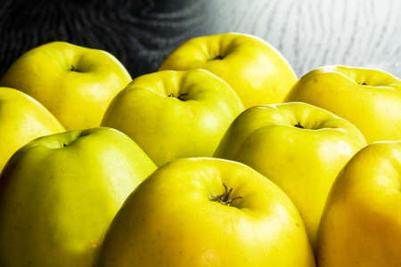 Golden apples lined up on a black backgroundの写真素材
