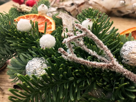 Christmas wreath on wooden table top view. Top down view of florist's worktable. Making of Christmas wreath. Getting ready for Christmas. Christmas tree decoration toys, gift box and scissors over rustic wood table background, top viewの写真素材