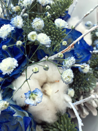Close-up Beautiful Bouquet. Bouquet of flowers Blue roses covered with snow, cones, fir branches, cotton ball.. Beautiful Winter bouquet of white and blue flowers. Closeup.の写真素材
