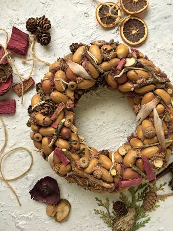 Rustic wreath with dry acorns, cones on a white background, sunny autumn day. House decoration.の写真素材