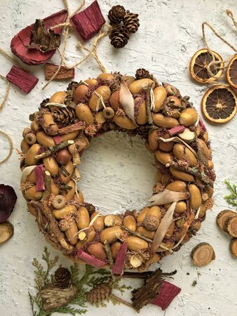 Rustic wreath with dry acorns, cones on a white background, sunny autumn day. House decoration.の写真素材