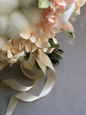 Flower arrangement cotton blooms in white, roses in a beautiful blend of peach, light peach and white color, preserved hydrange. Preserved flower bouquet close up.の写真素材