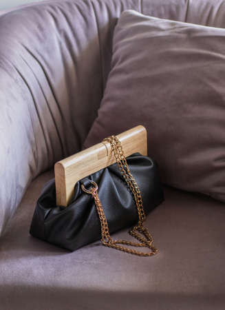 Stylish evening womens clutch bag black color with wooden closure on dusty pink background. Fashionable womens bag.の写真素材
