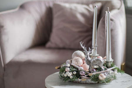 Christmas decor composition of fir-Tree branches nobilis , with silver candles and decorative deer on wooden stand. Interior decor for the Christmas New Year holidays.の写真素材