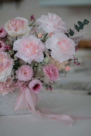 Beautiful bouquet of peonies and pink roses on the table. In the background is the interior of a modern white kitchen. Concept of home comfort.の写真素材