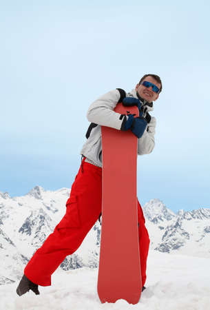 Pretty man with red snowboard in red pantsの写真素材