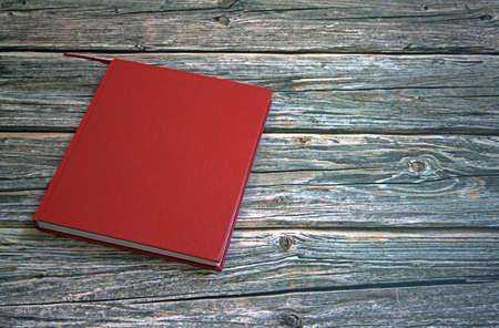 Book with red cover on wooden table against white backgroundの写真素材