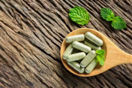 Herbal medicine in capsules powder herb on wooden spoon with mint leaf on rustic wooden table for healthy eating, dieting food for good happy life livingの写真素材