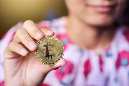 Hand holding bitcoin with trading market chart on smiling showing growth uprising of cryptocurrency coinsの写真素材