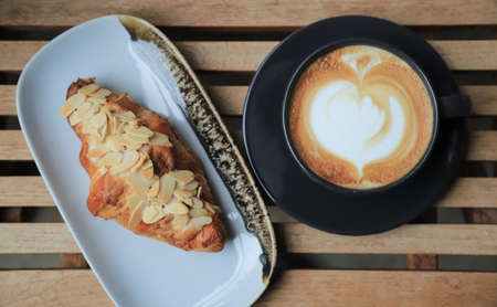 Selective focus on almond crossiant with hot coffee on background in home morning eating