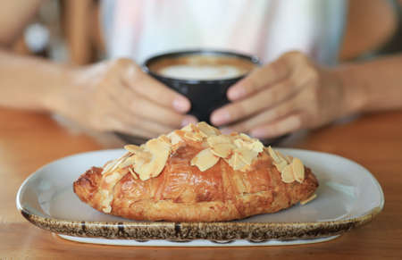 Selective focus on almond crossiant with hot coffee on background in home morning eating