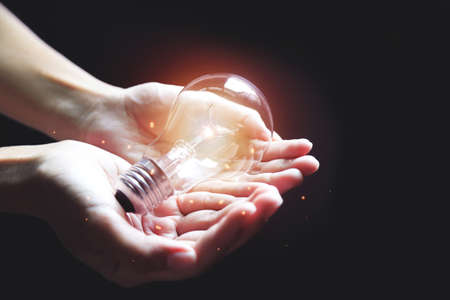 Shining light bulb on hand with growing light for creative idea using concept. Creativity photo for inspiration thinking of way.の写真素材